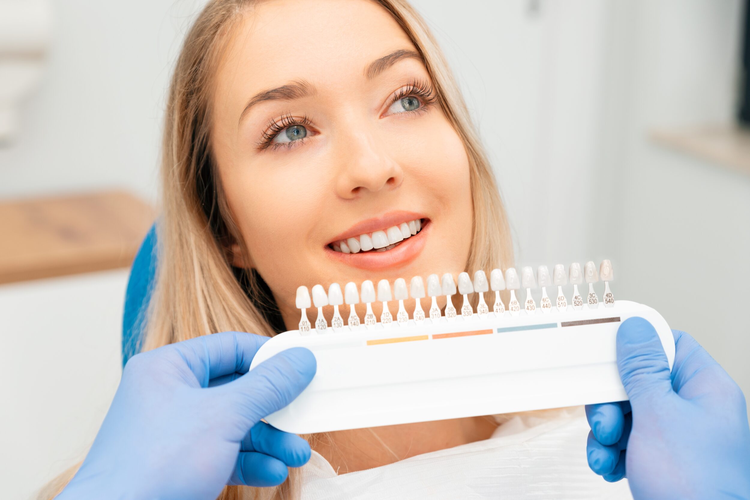 Dentist and patient selecting veneer shade to match teeth whitening results during cosmetic dentistry consultation