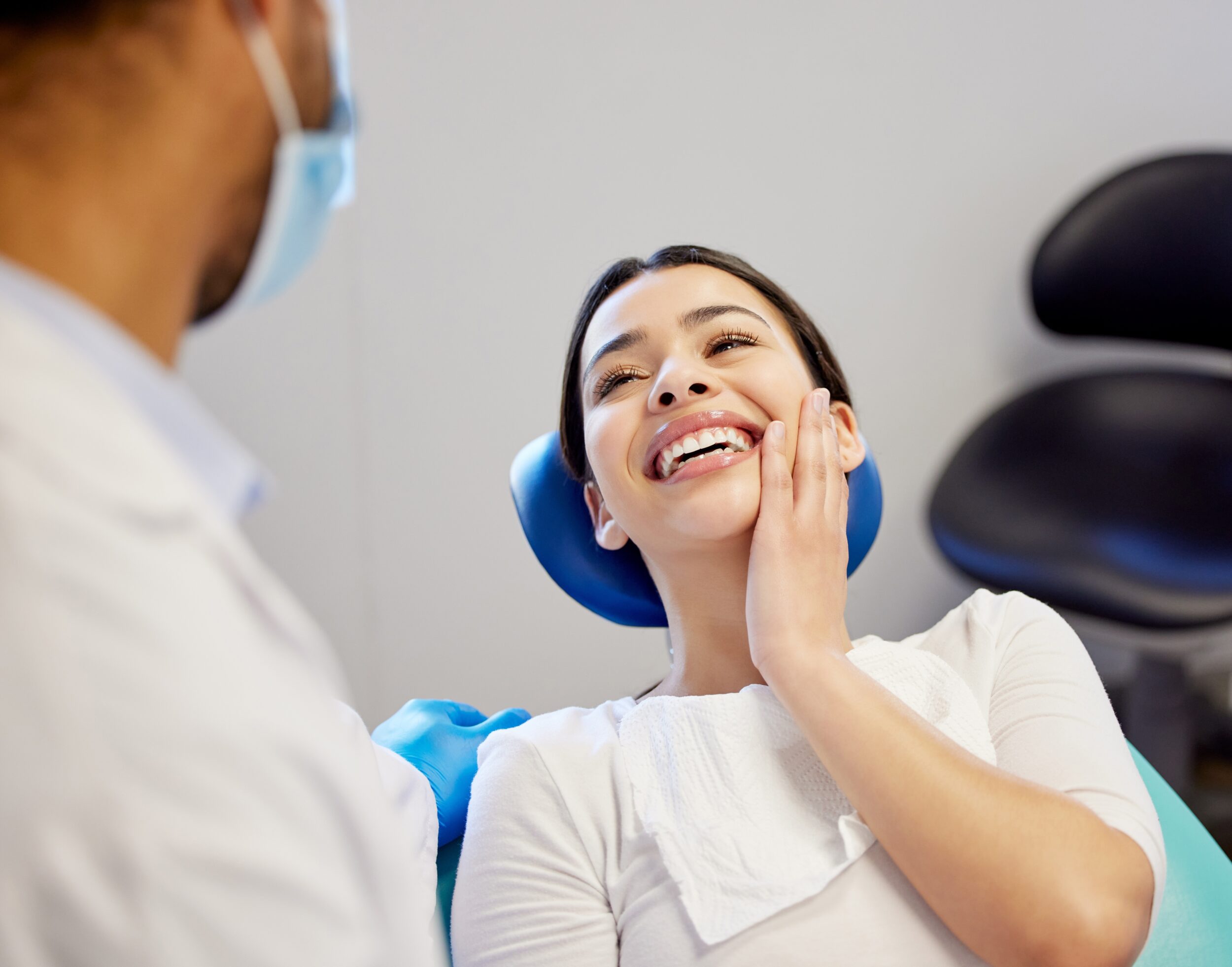Smiling woman at dental clinic with dentist, feeling satisfied after cosmetic dental treatment such as tooth removal or root canal