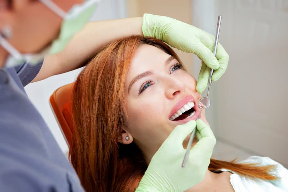 a smiling patient in a dental chair gets a teeth cleaning