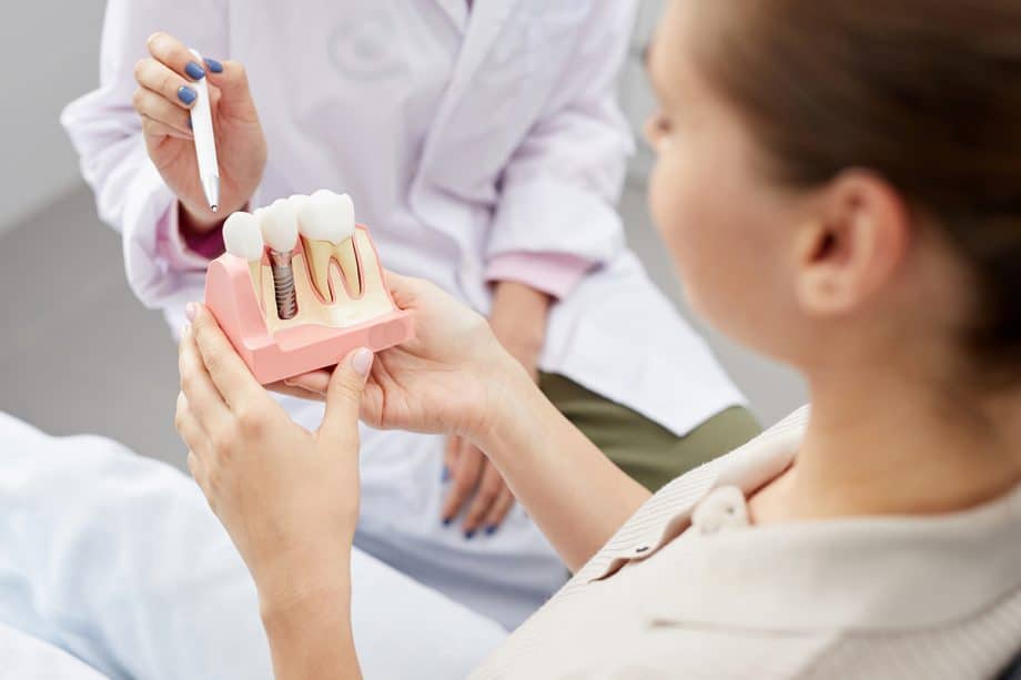 dentist shows a dental implant model to a patient