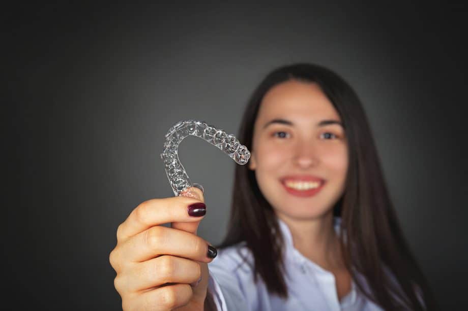 a person holds an invisalign tray up to camera